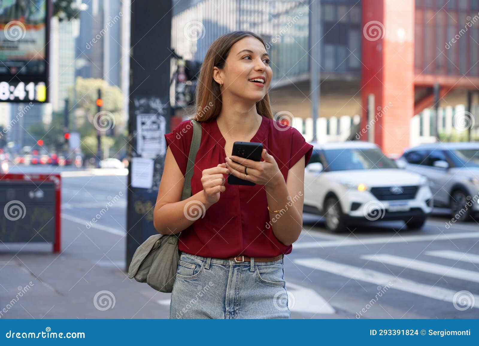 close-up of brazilian business woman hail a vehicle using mobile app looking to the side on paulista avenue, sao paulo, brazil
