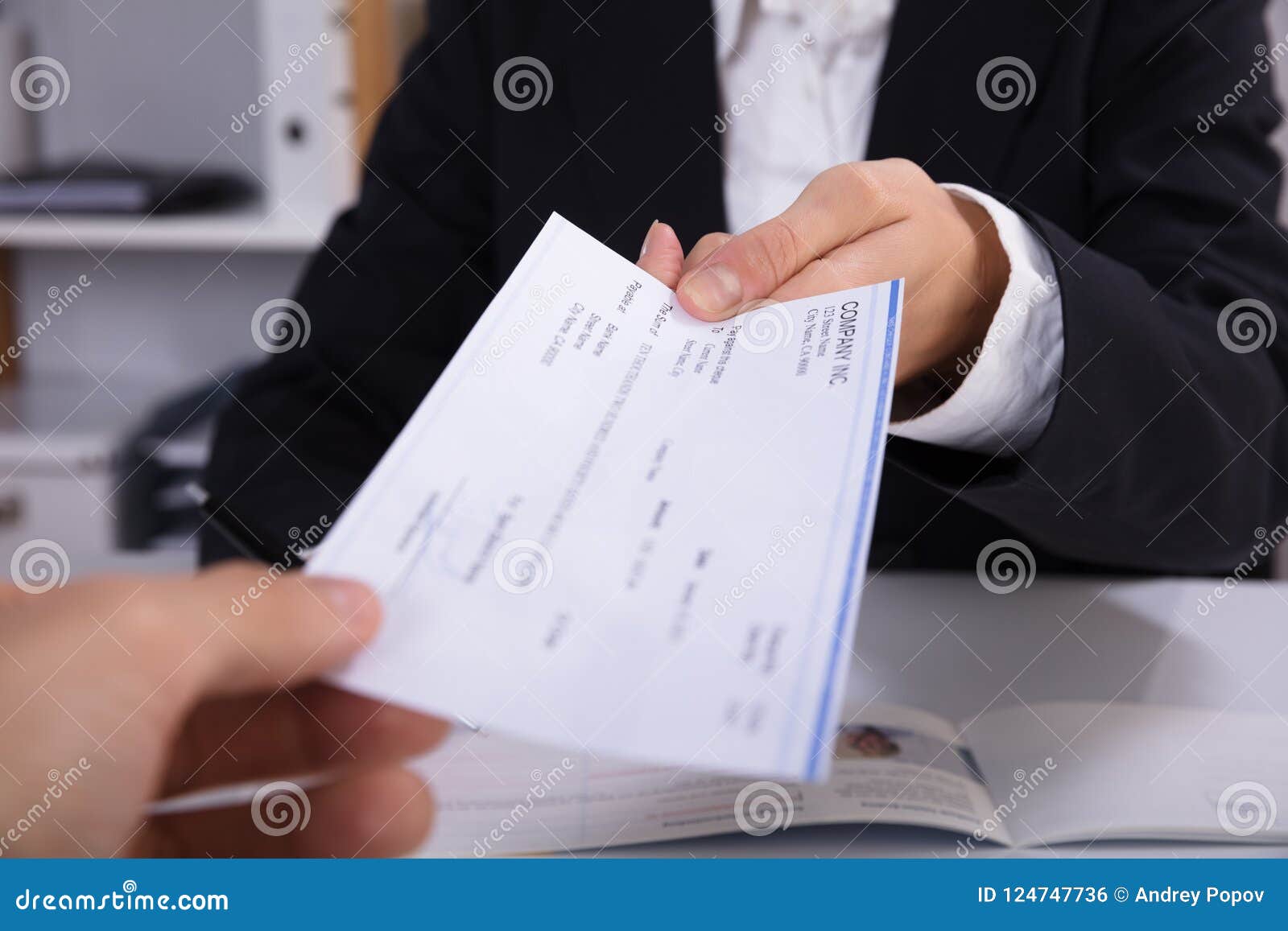 business woman handing over cheque to her colleague