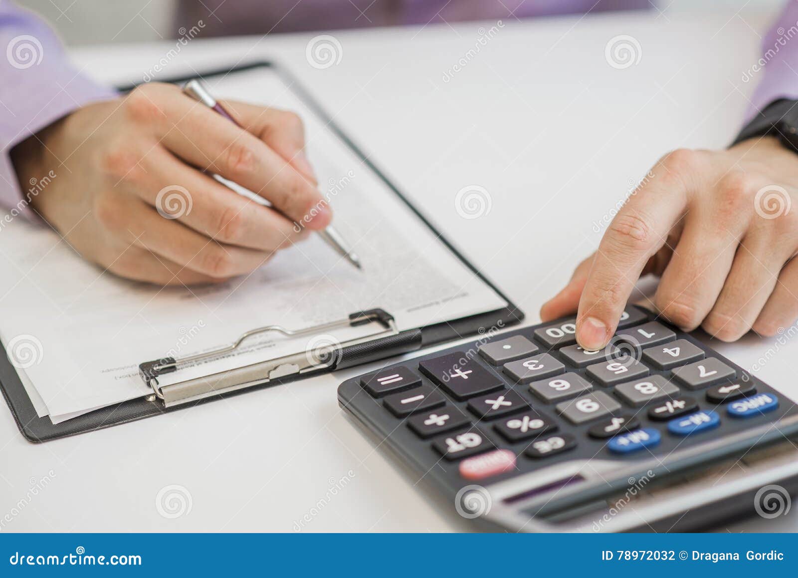 Closeup of Businessman Calculating Invoices Using Calculator Stock