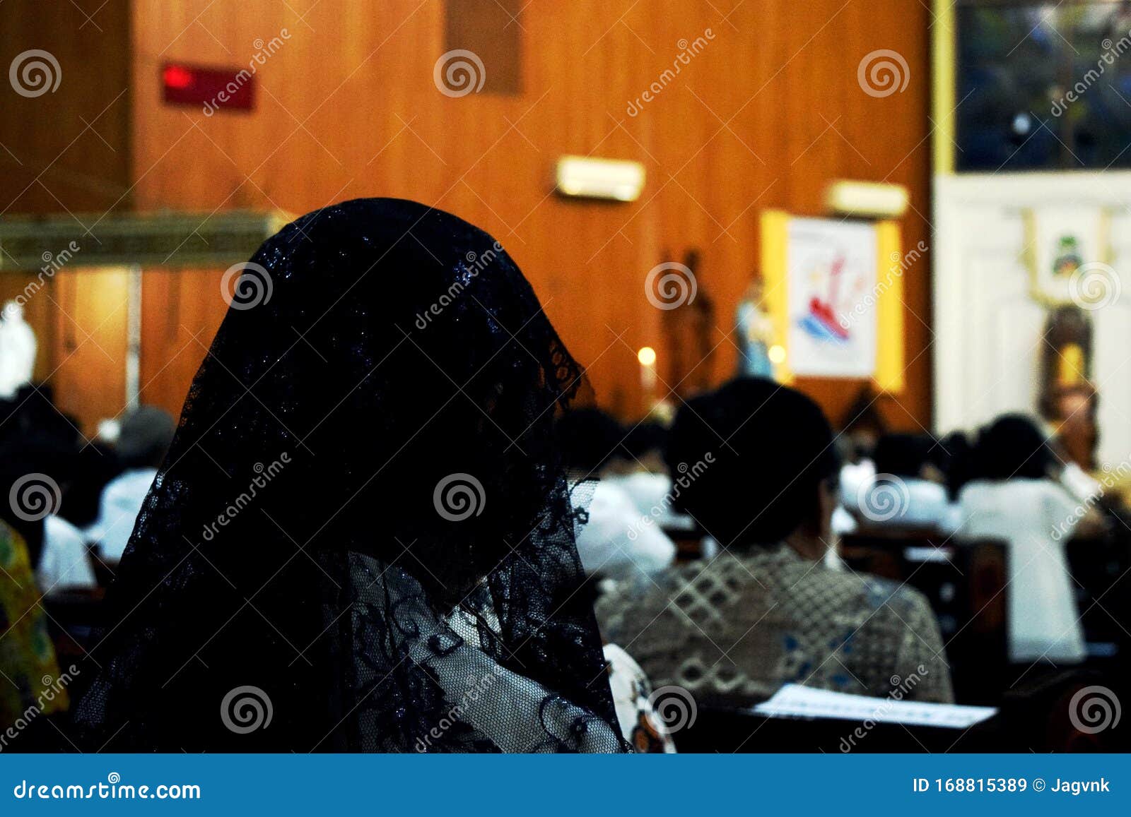 a woman wearing a black mantilla praying at church