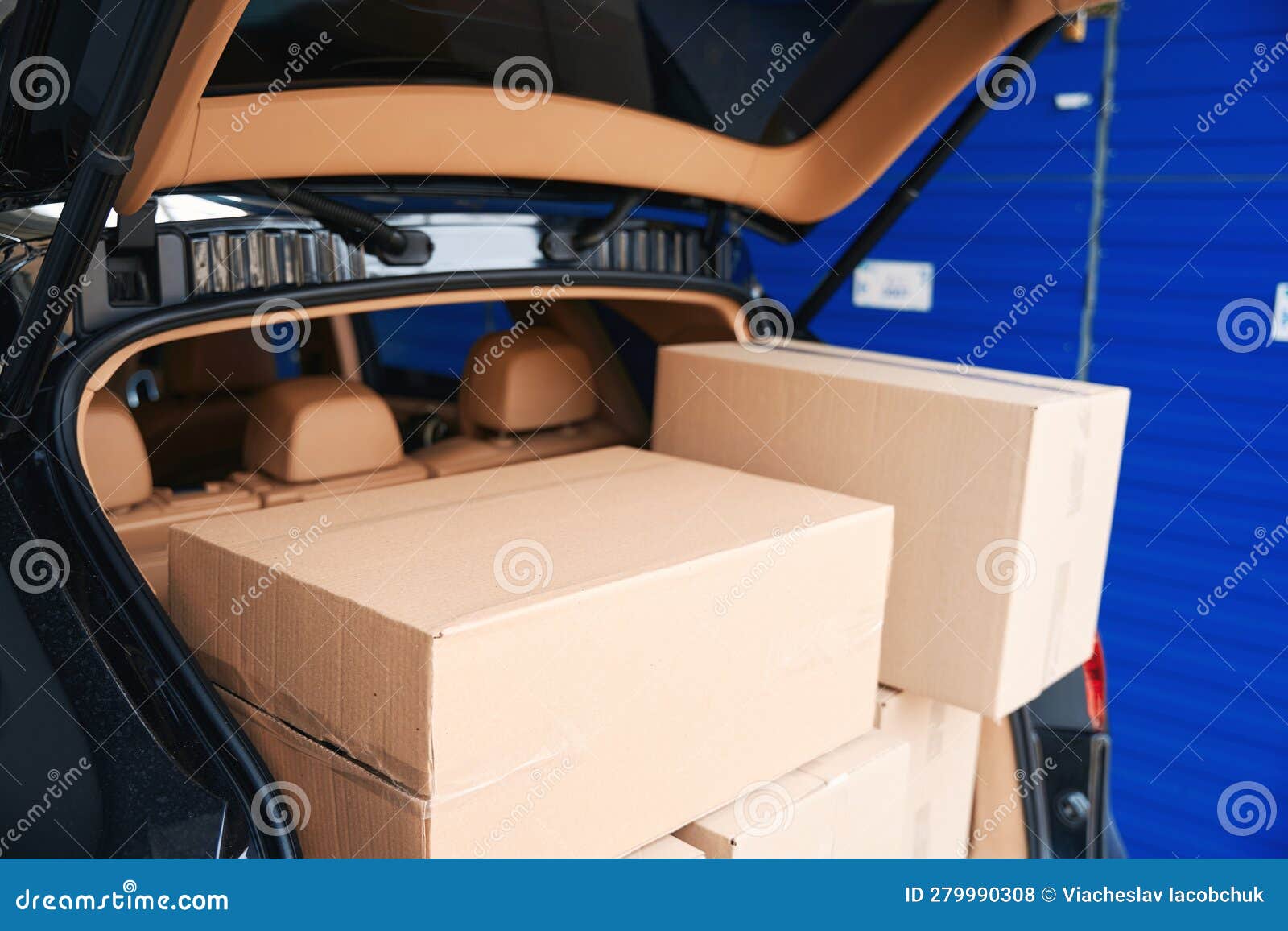 Closeup of Cardboard Boxes in Trunk of Car into Warehouse Stock Photo