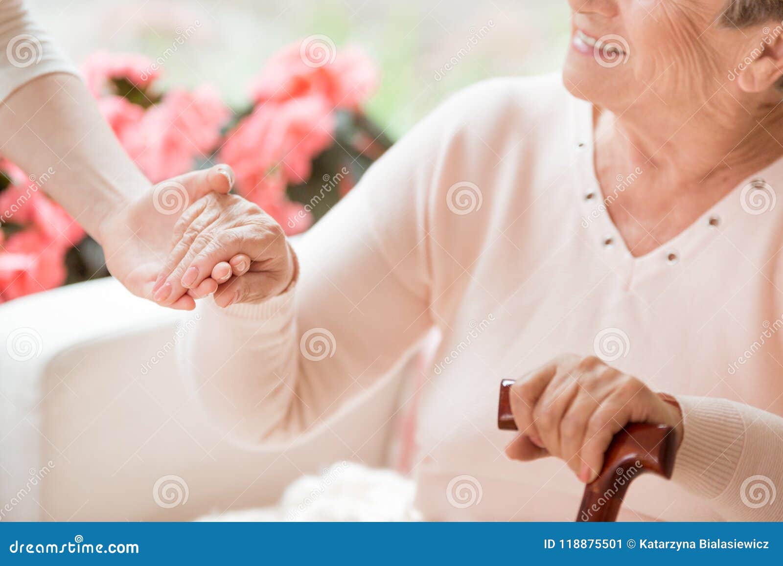 close-up of caregiver supporting smiling senior woman with walki