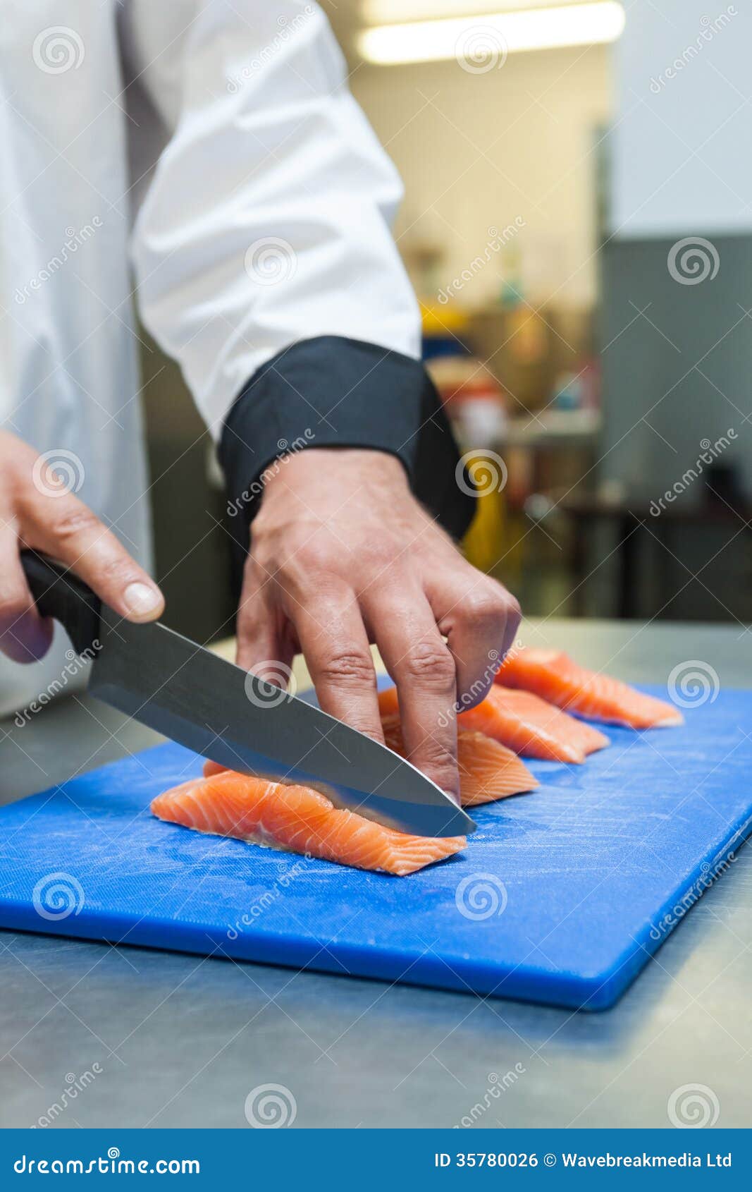 Close Up of Chef Slicing Raw Salmon with Sharp Knife Stock Photo
