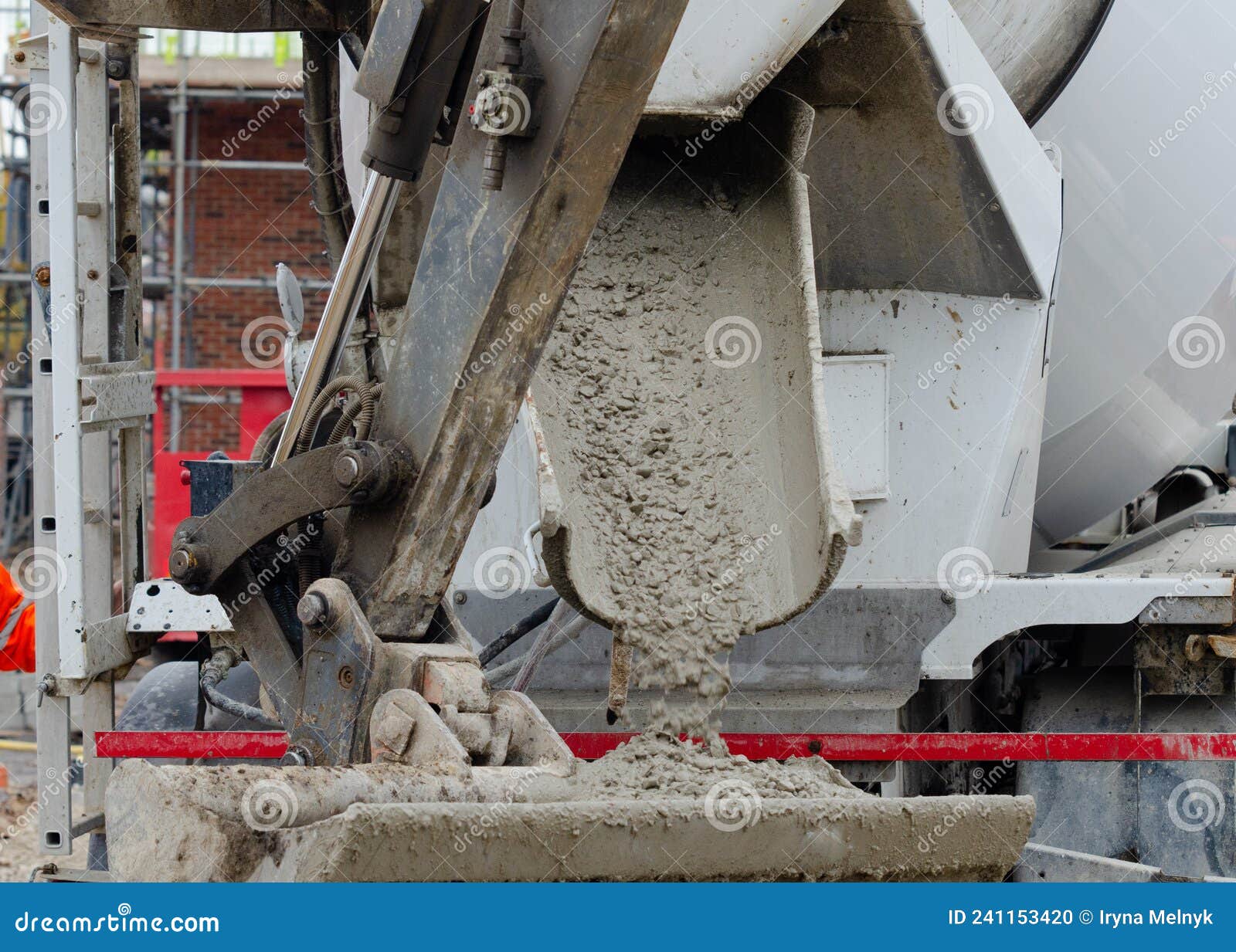 close up of concrete flowing into excavator bucket from delivery vagon