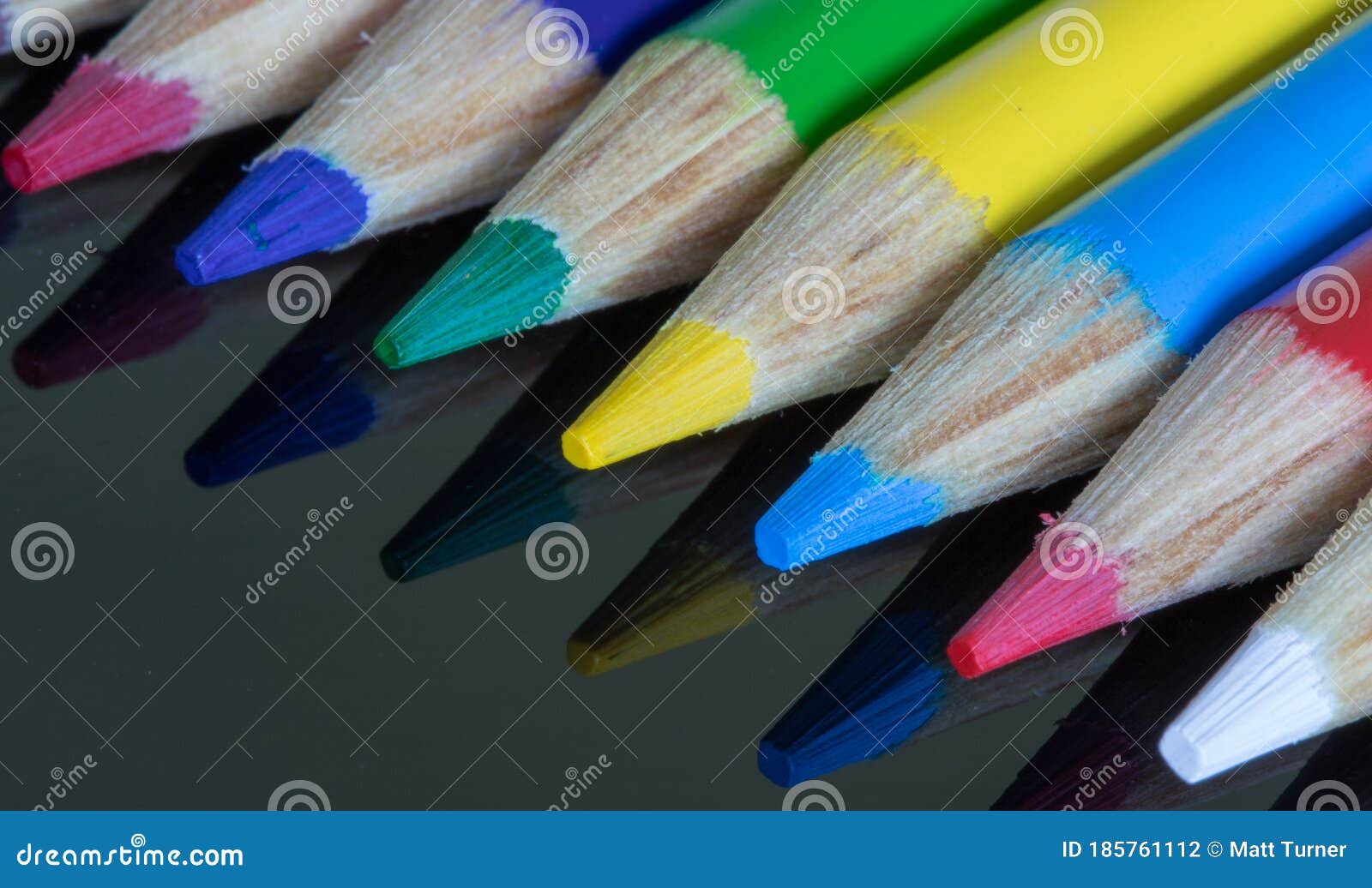 coloured pencil crayons on a black reflective surface