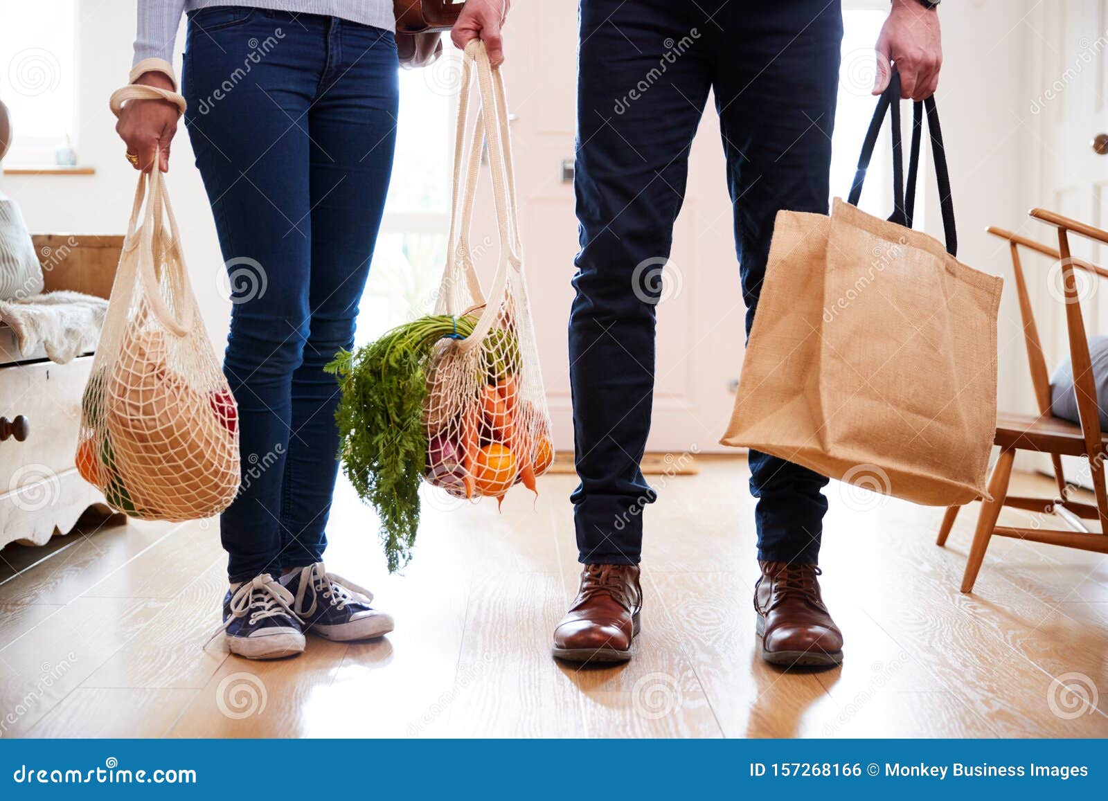 close up of couple returning home from shopping trip carrying groceries in plastic free bags