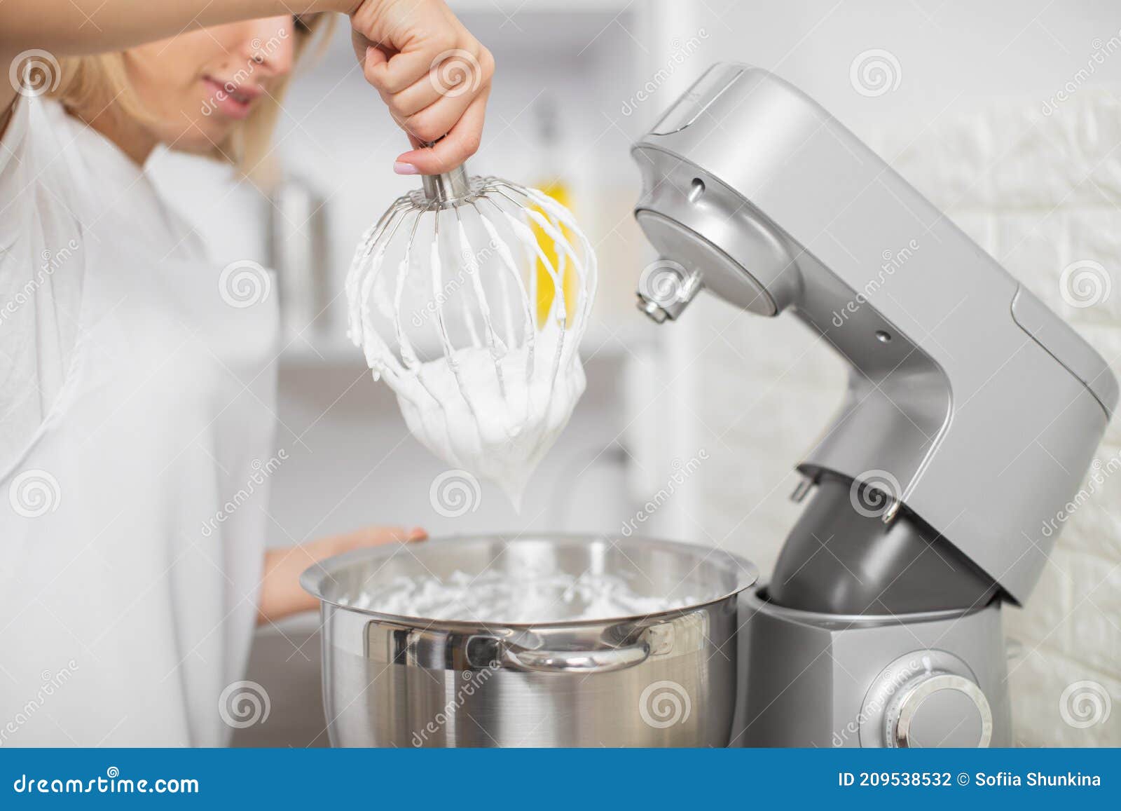 close up cropped indoor shot of professional female chef, making desserts at her pastry shop, remowing mixer whisk with