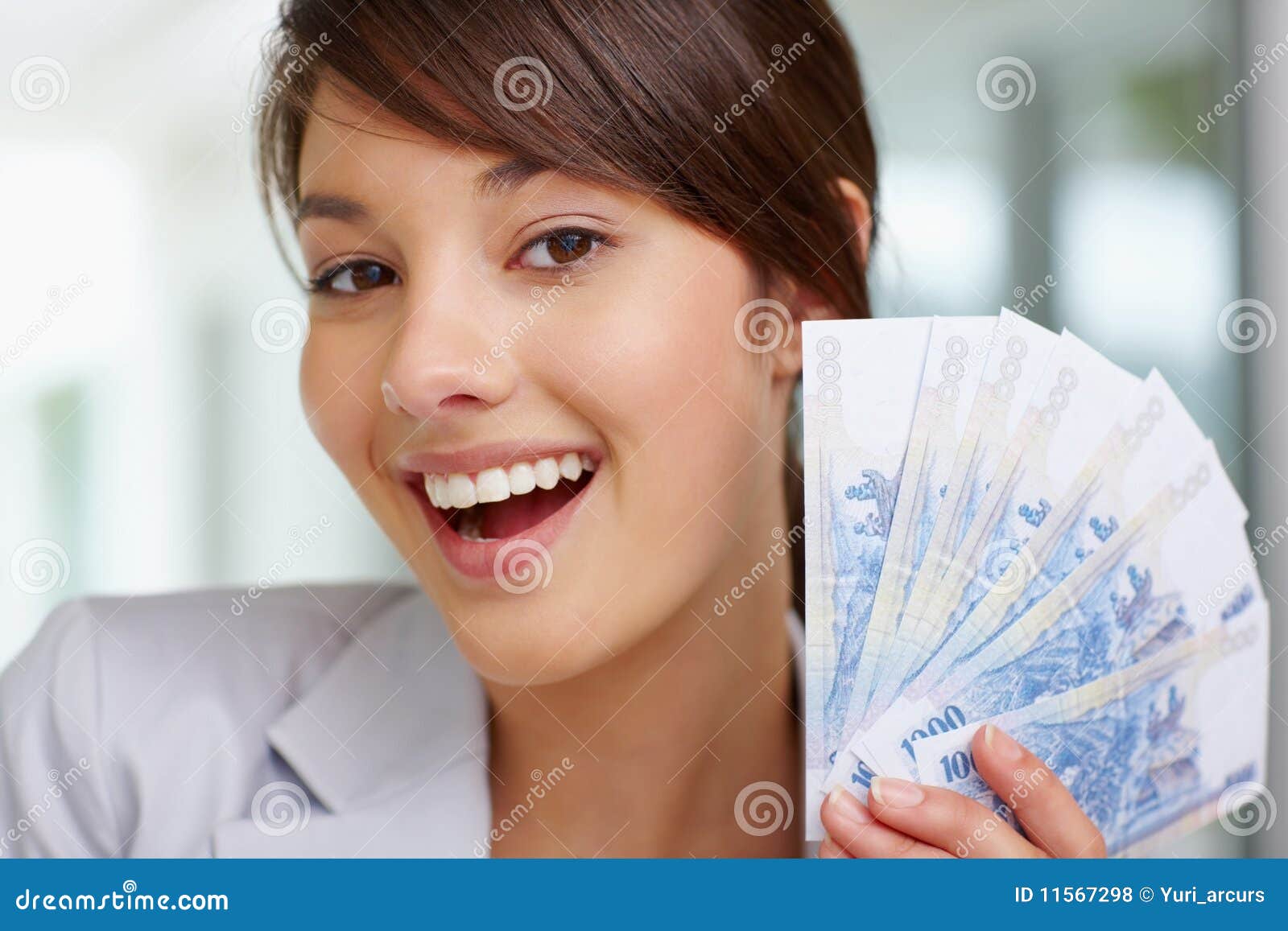 Close up de uma mulher com notas da moeda. Retrato do close up de uma fêmea nova feliz que prende um ventilador de notas da moeda