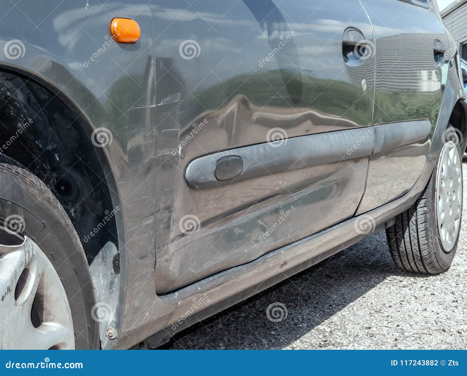 close up detail of a dented driver door from a car crash or automobile accident.