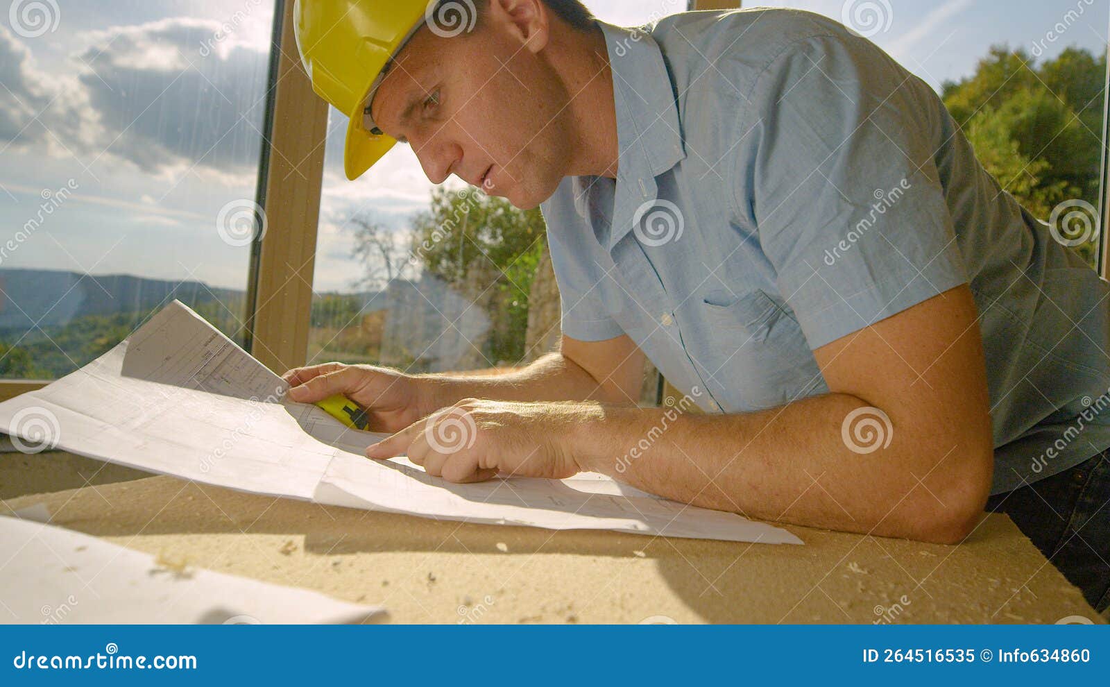 CLOSE UP Diligent Contractor Looks at the Blueprints Lying on His Workbench. Stock Image