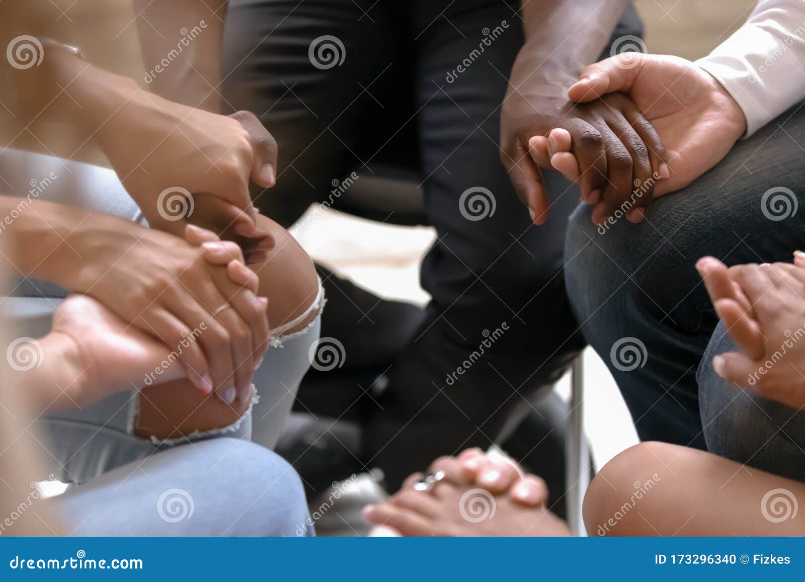 close up diverse people sitting in circle, holding hands