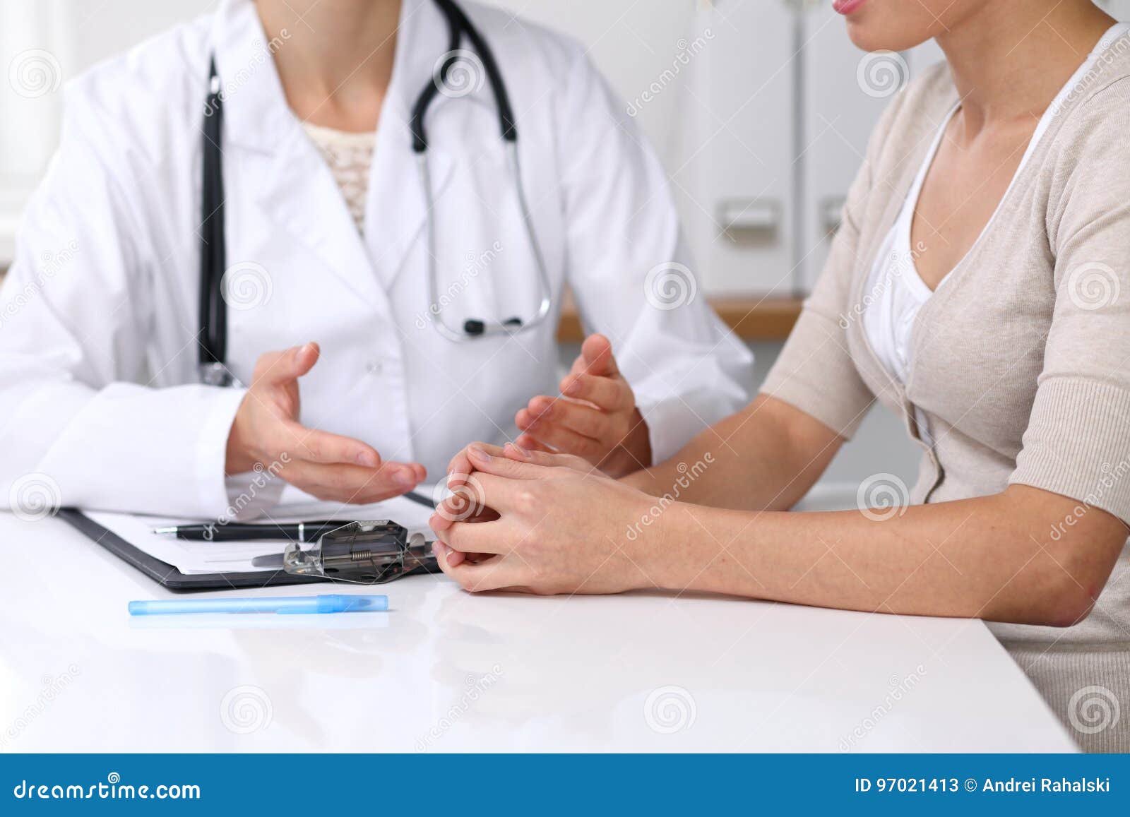 close up of doctor and patient sitting at the desk while physician pointing into medical form hystory. medicine a
