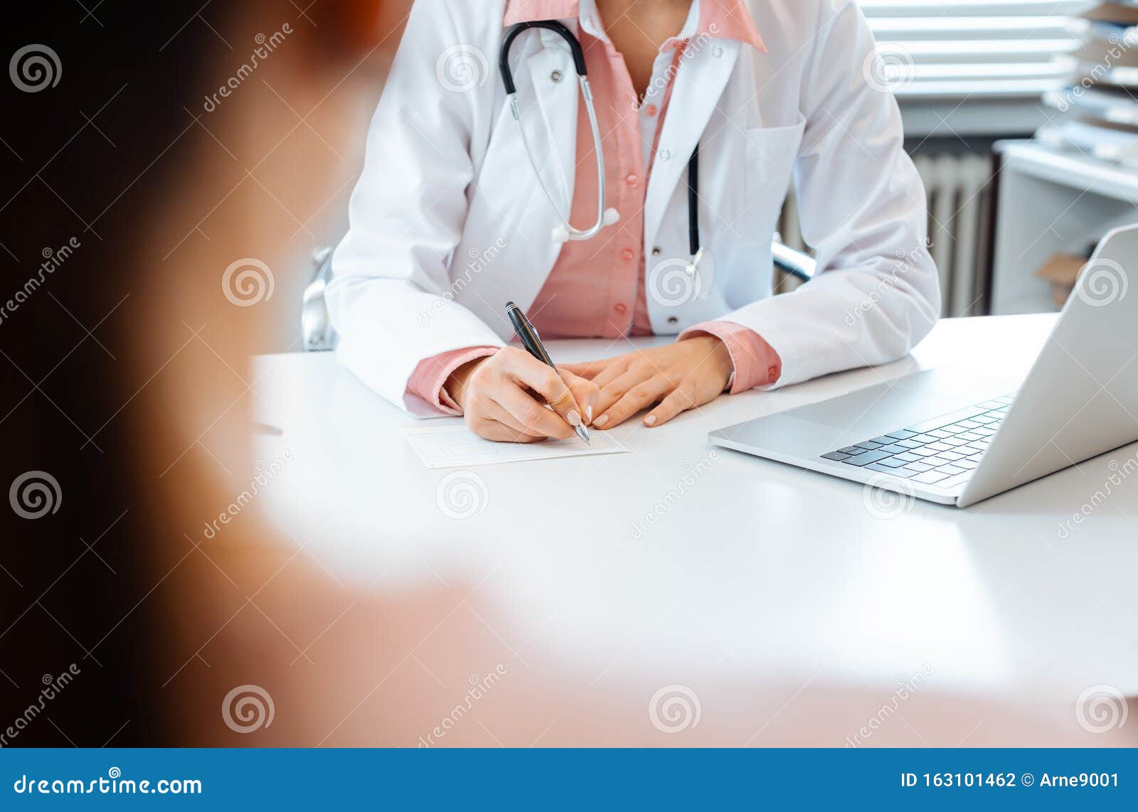 close-up of doctor taking notes while having appointment with patient
