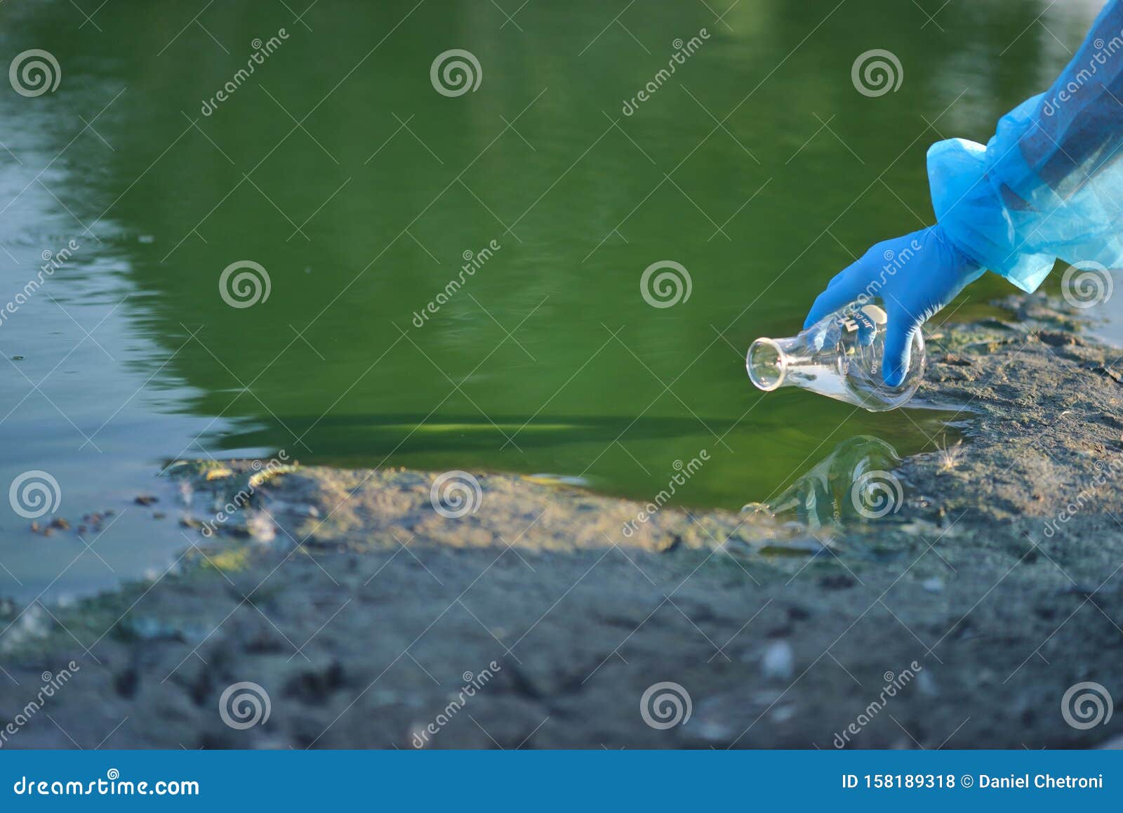 close-up environmentalist hand of a researcher in a process of taking a sample of contaminated water from a lake