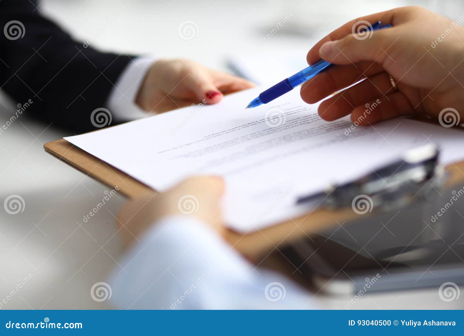 Close up of an executive hands holding a pen and indicating where to sign a contract at office.