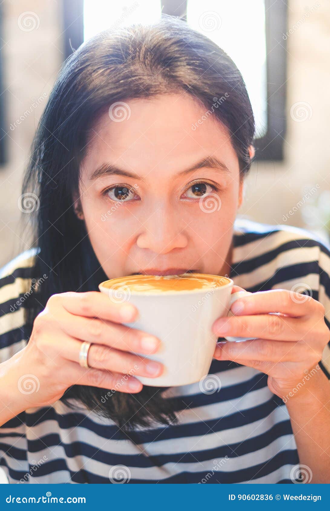 close up face of asian woman sip hot cappuccino coffee in cafe s