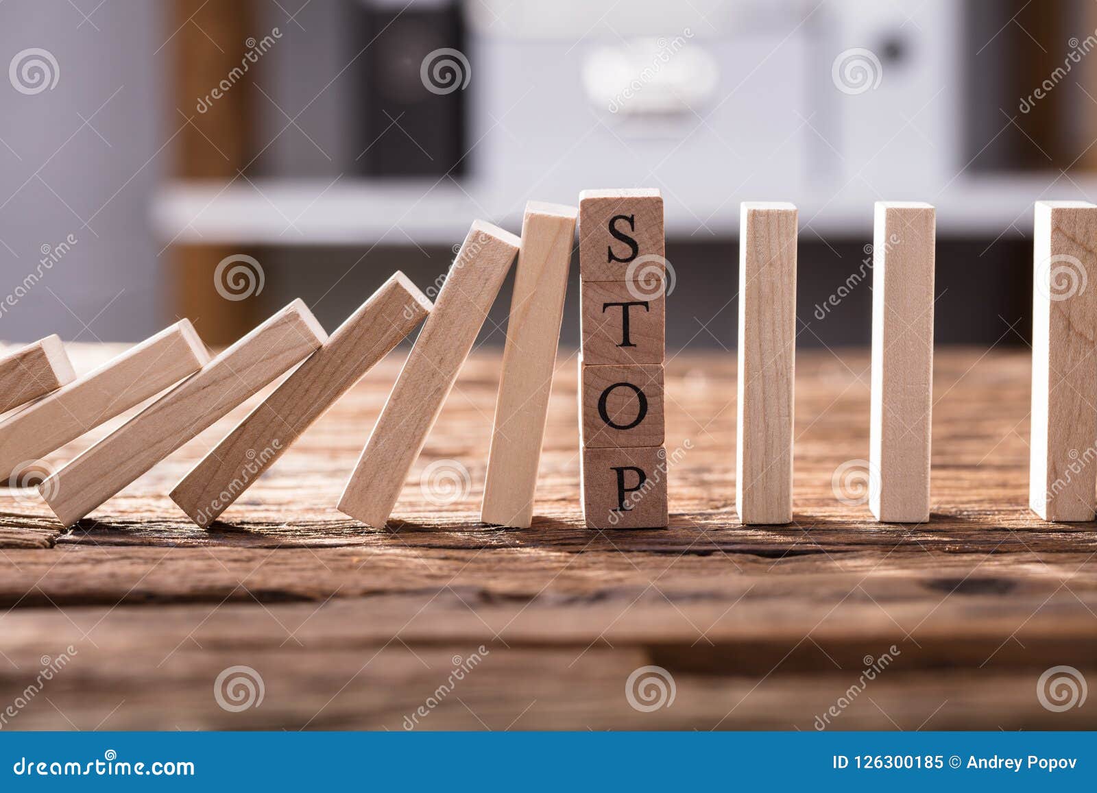 falling dominos stopped by wooden blocks showing stop text