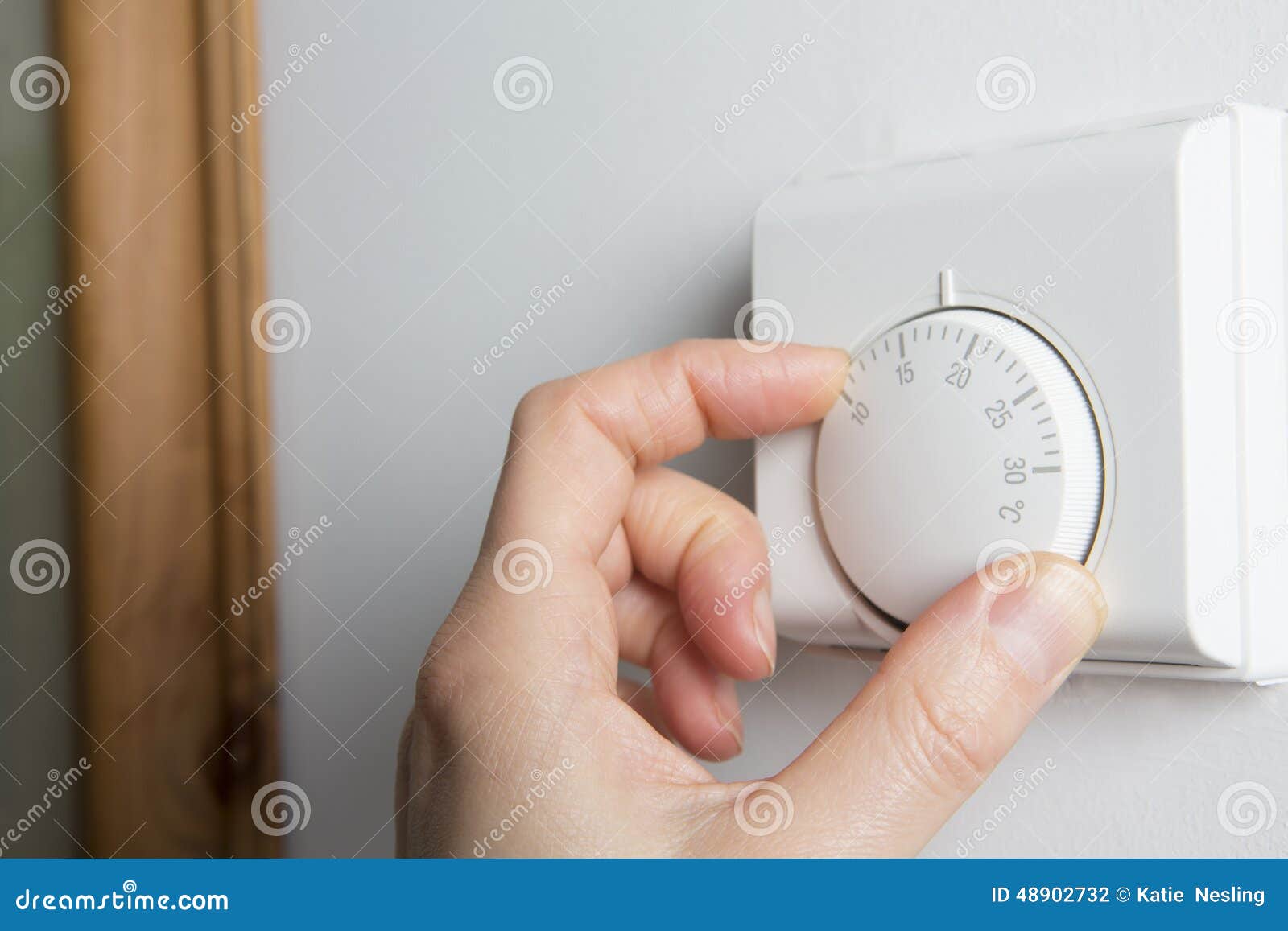 close up of female hand on central heating thermostat