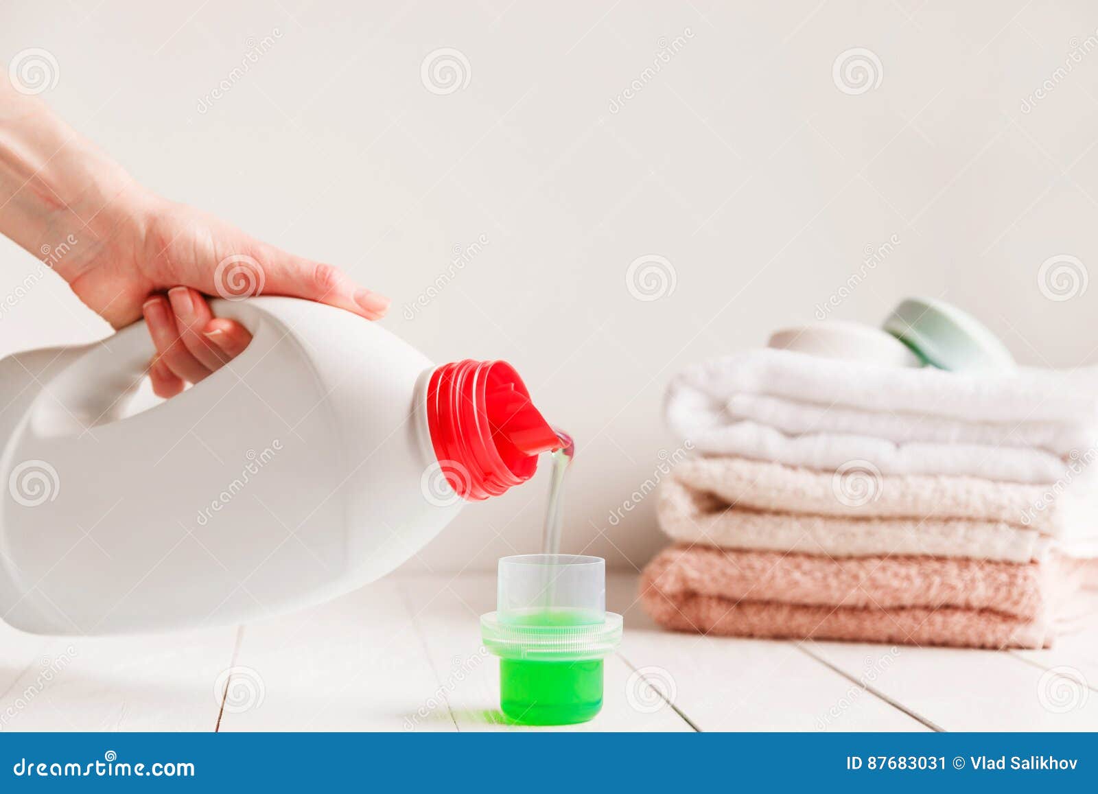 Close Up of Female Hands Pouring Liquid Laundry Detergent into Cap on