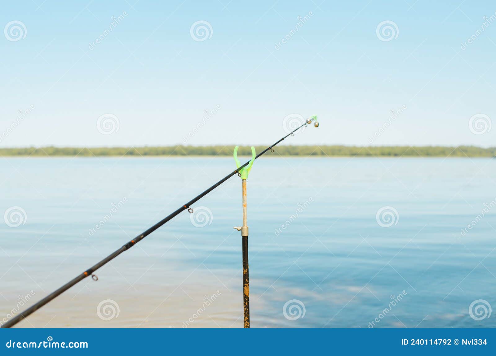 Close-up of Fishing Rod with Bell on Stand on Lake Outdoors