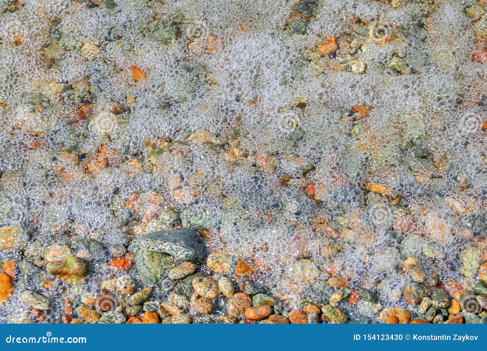 close up of foam and pebbles on the summer beach. surf.