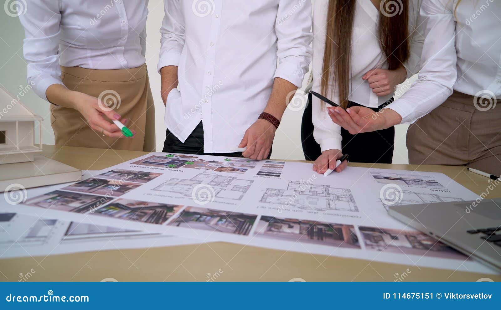 Close Up of Four Architects Discussing Plan Together at Desk with