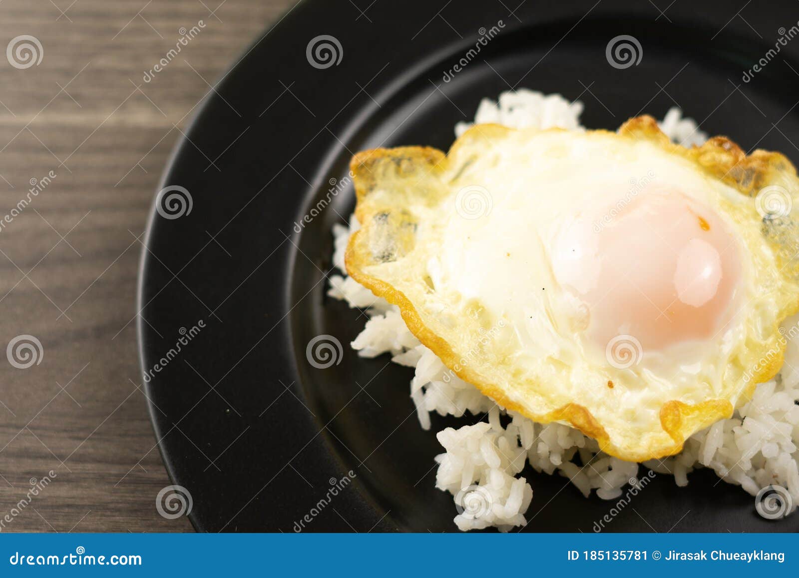 Closeup of a Fried Egg on a White Rice in a Black Plate in the Right