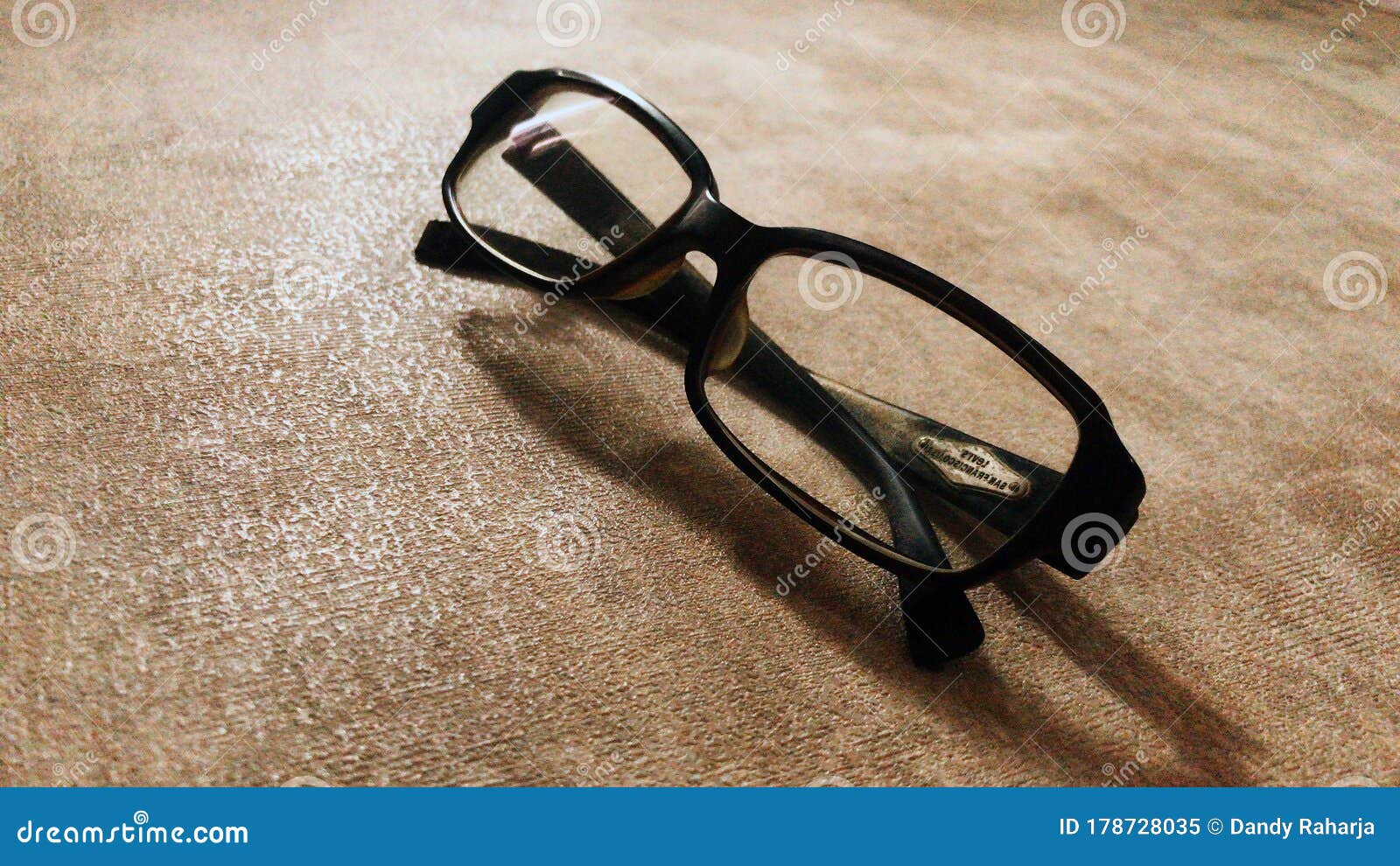 Glasses With Folded Arches Lie On A Yellow Surface. Above Lies A Lens