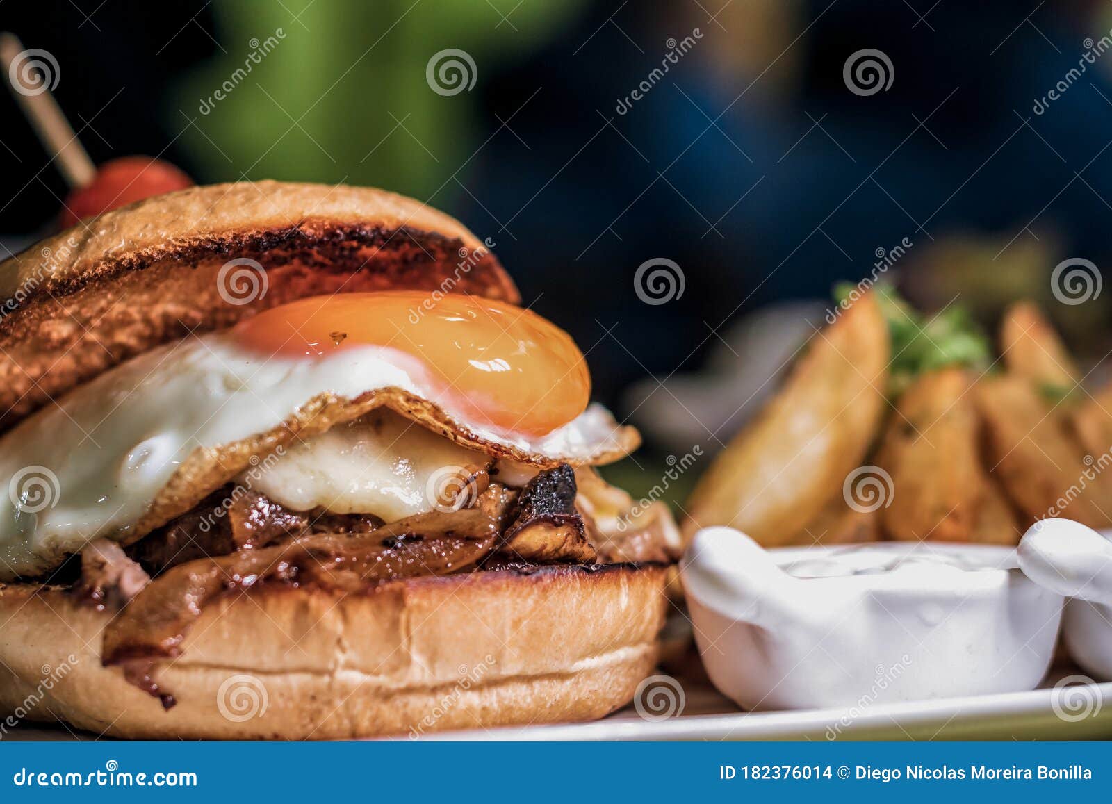 close up on a gourmet burger with eggs and potato fries