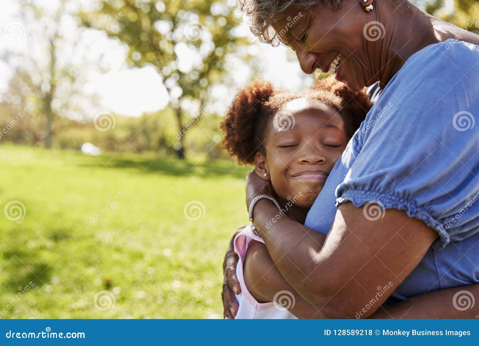 close up of granddaughter hugging grandmother in park
