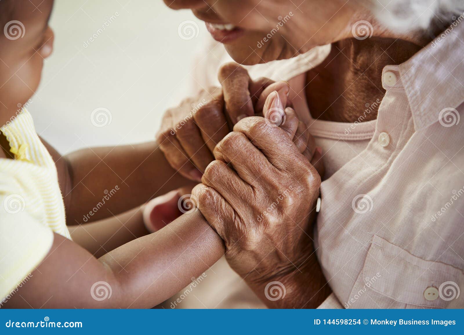 close up of grandmother holding hands with baby granddaughter playing game together