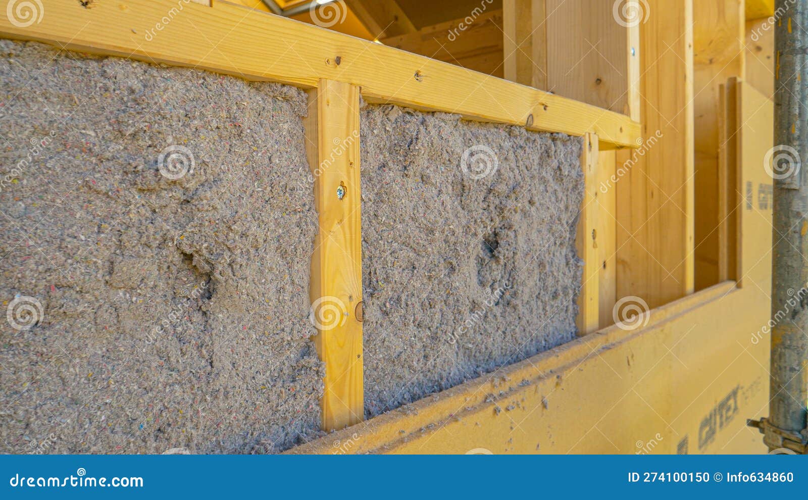 close up: ecofriendly cellulose insulation fills up a frame on a wooden wall.