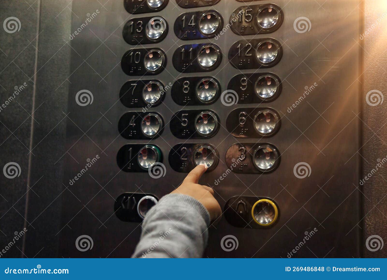 close-up hand of little child pressing button of number two floor in modern elevator