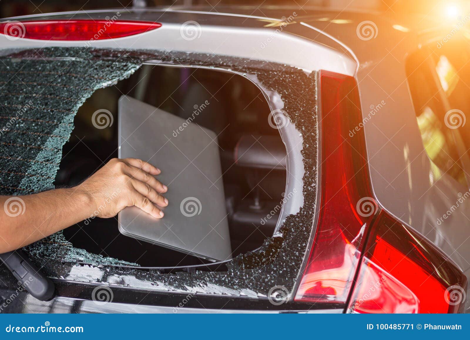hand stealing laptop from back side of car which rear glass broken