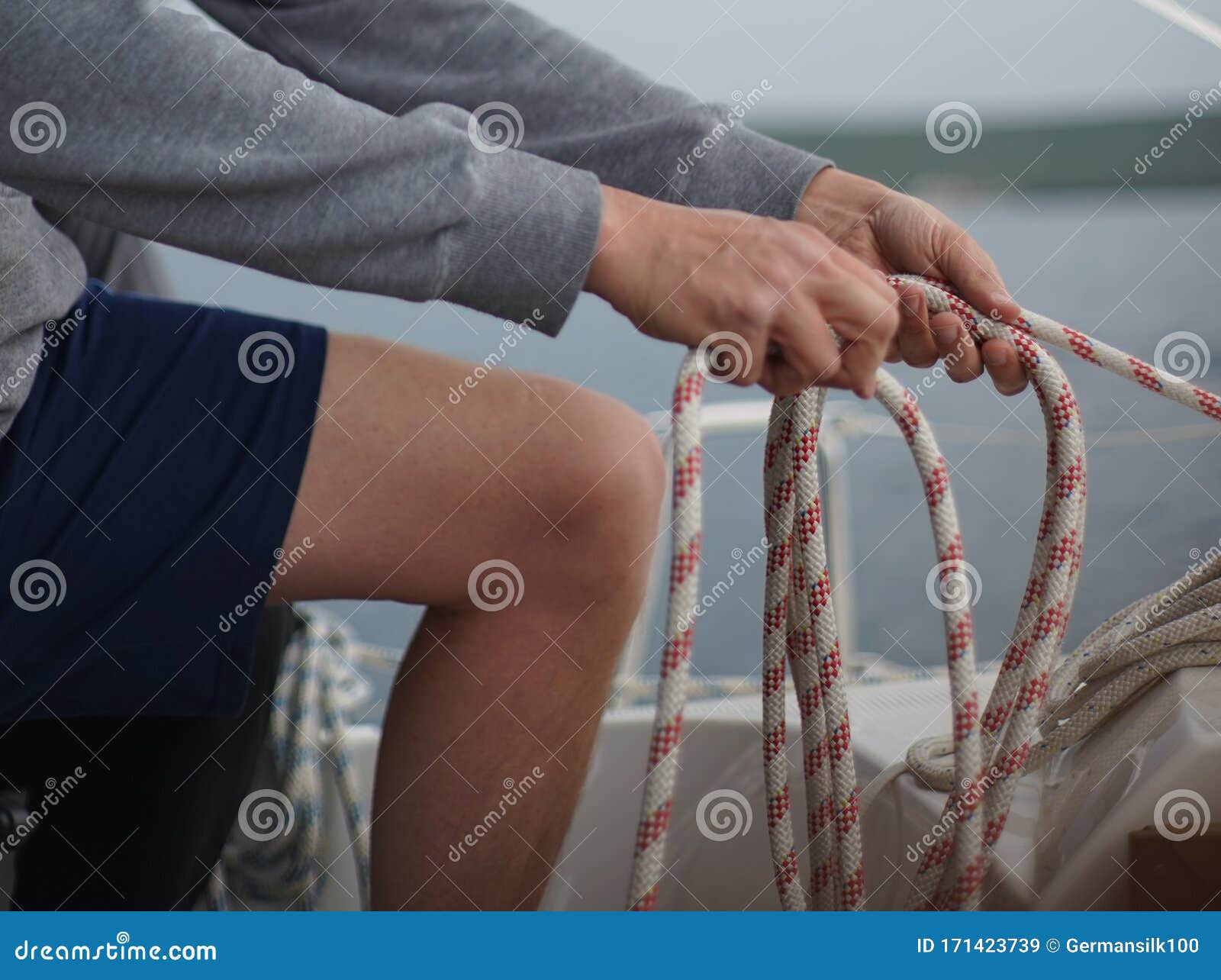close up of hands coiling up a rope, the halyard