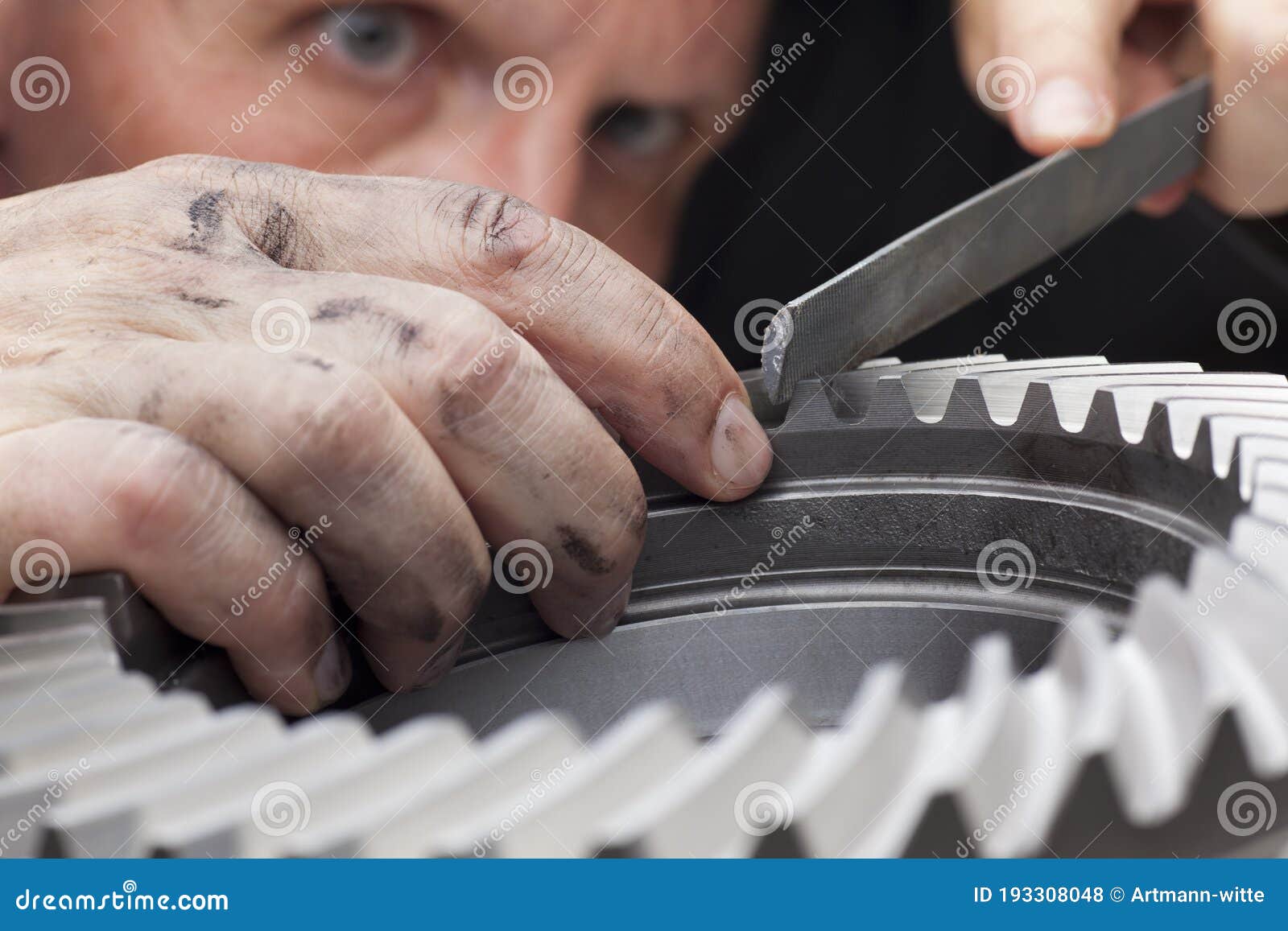 close-up of hands of a mechanic repairing a cog wheel with a rasp