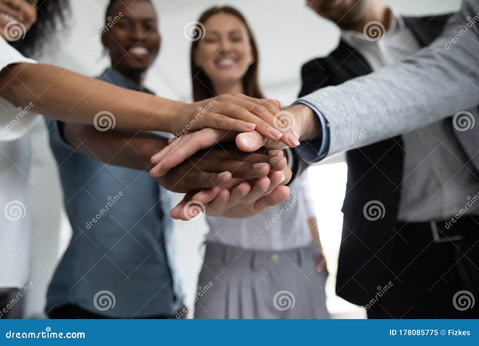 close up happy diverse business people putting hands together.