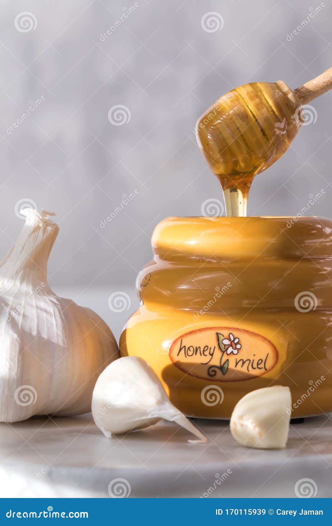 A Close Up of a Honey Dipper Dripping with Honey into a Honey Pot and