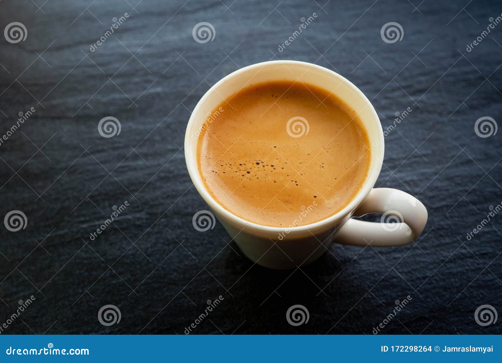 hot coffee cup with foam crema on a stone board back color with copy space