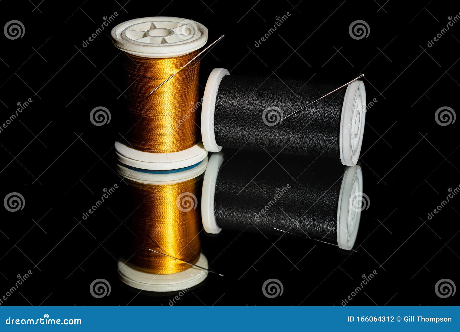 A Close Up Image of 2 Spools of Sewing Thread in Black and Gold Set