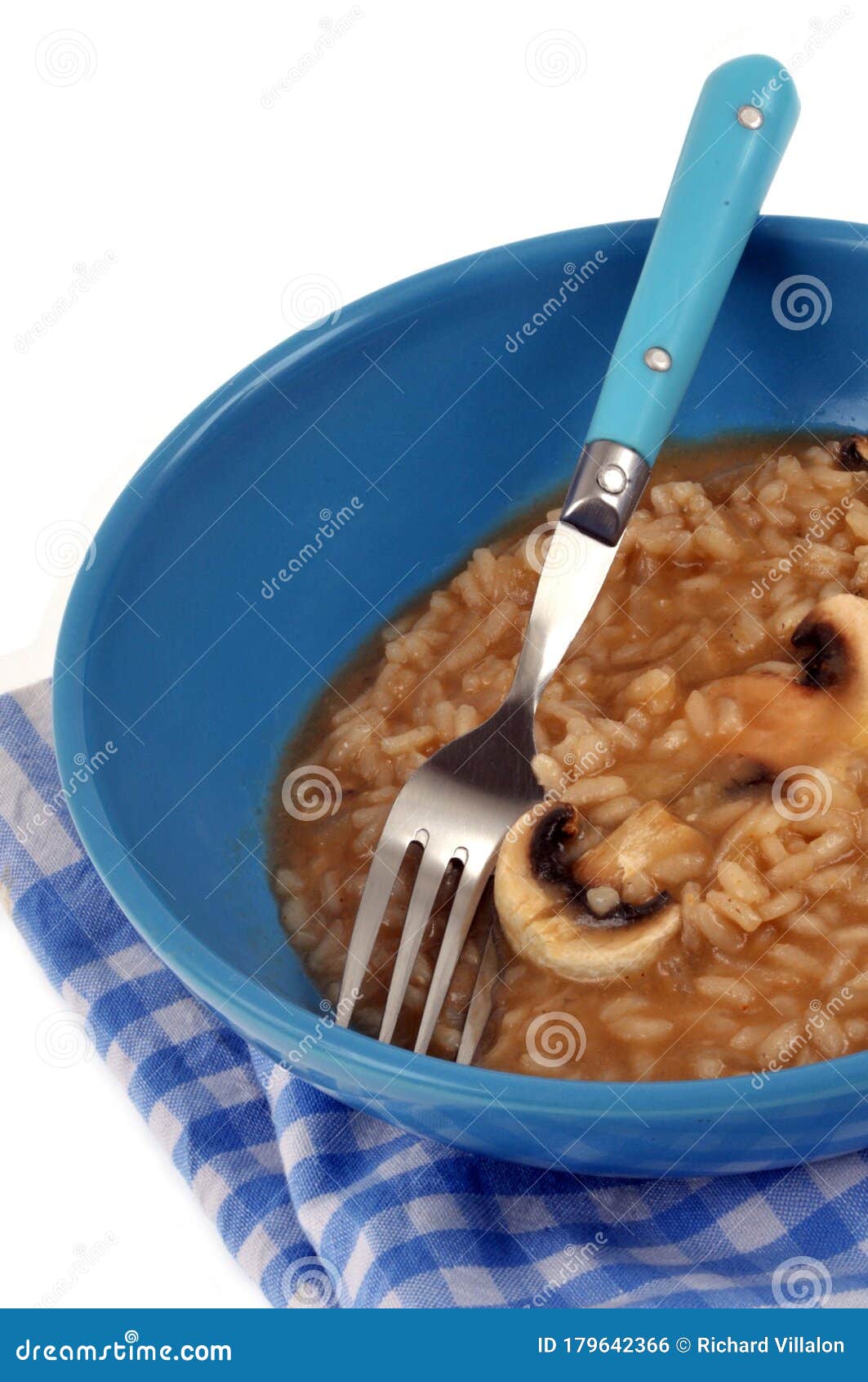plate of mushroom risotto with fork close-up on white background
