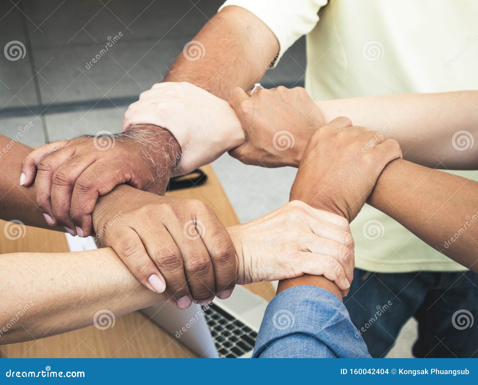 close up of joining hands of businessman in unity cross processing background; expression for cooperation without sexual discrimin