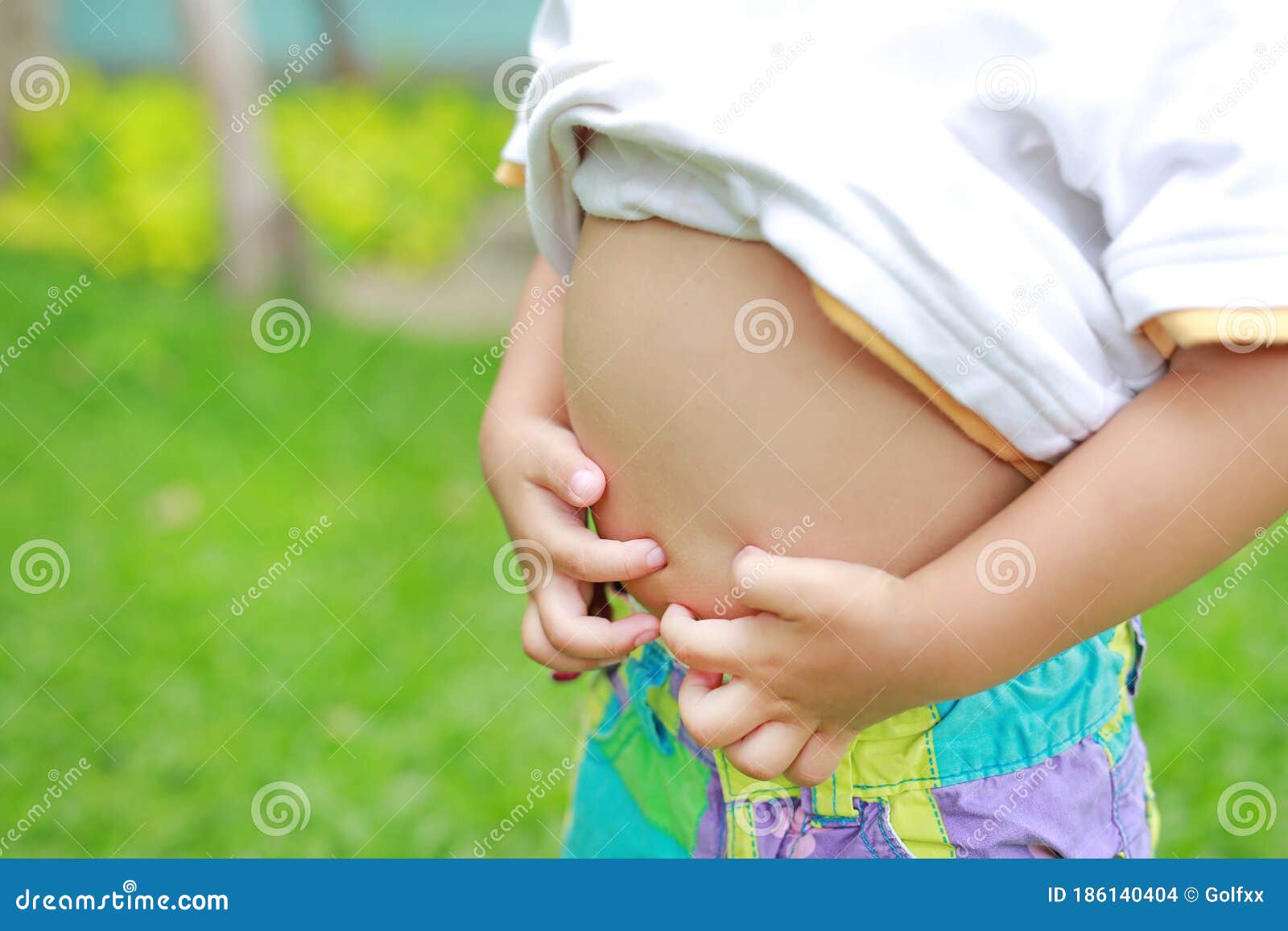 close up little boy with stomach ache, child holding hands on his belly