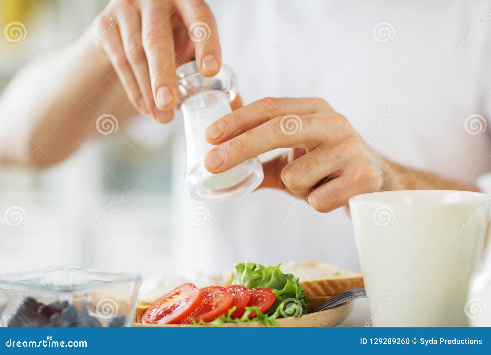 close up of male hands seasoning food by salt mill