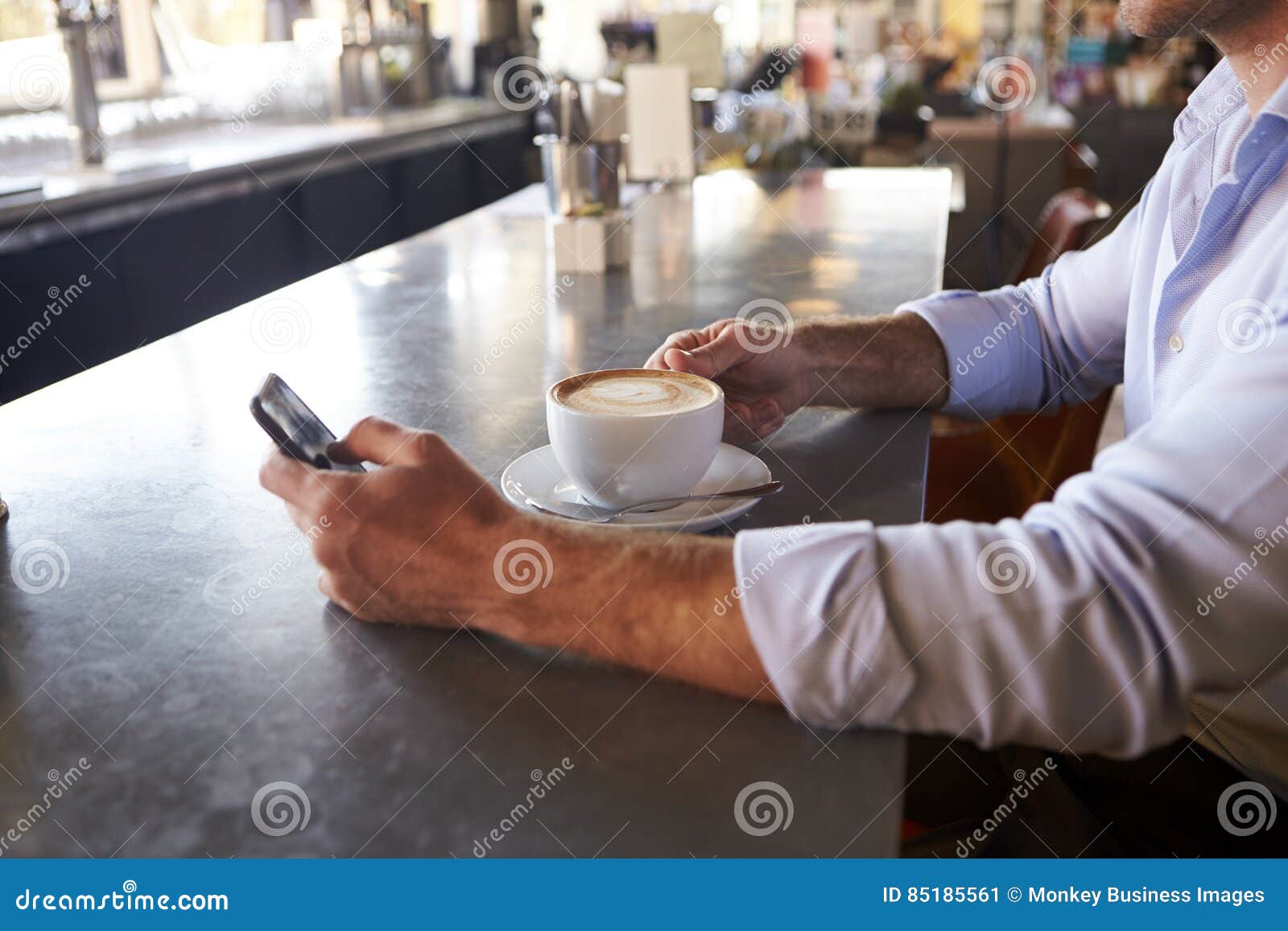 close up of man checking messages on phone in coffee shop