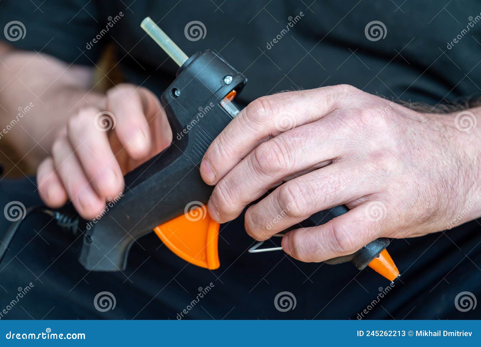 Closeup of a Man Holding a Glue Gun. a Grown Man with a Hand Tool