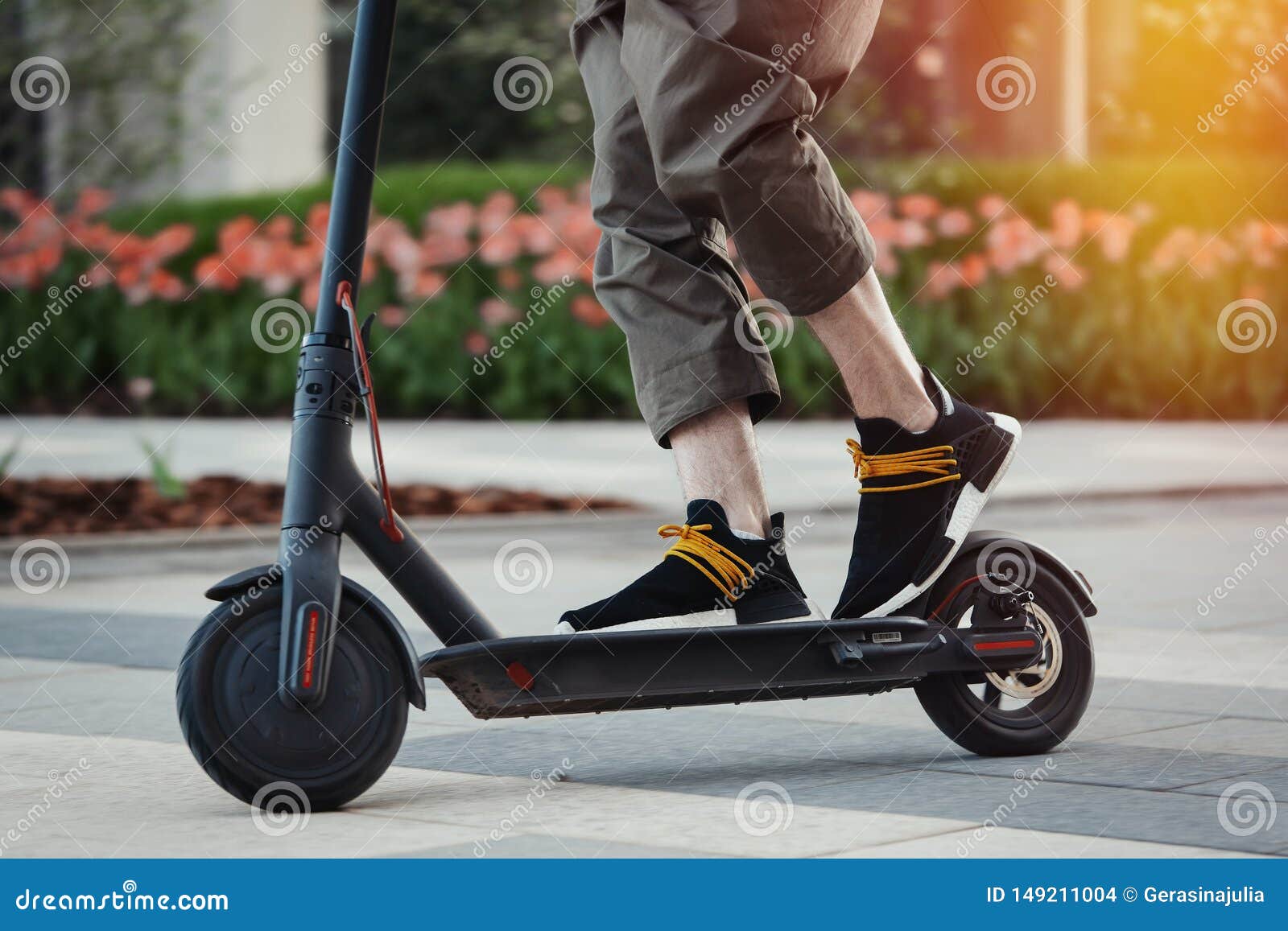 close up of man riding black electric kick scooter at beautiful park landscape