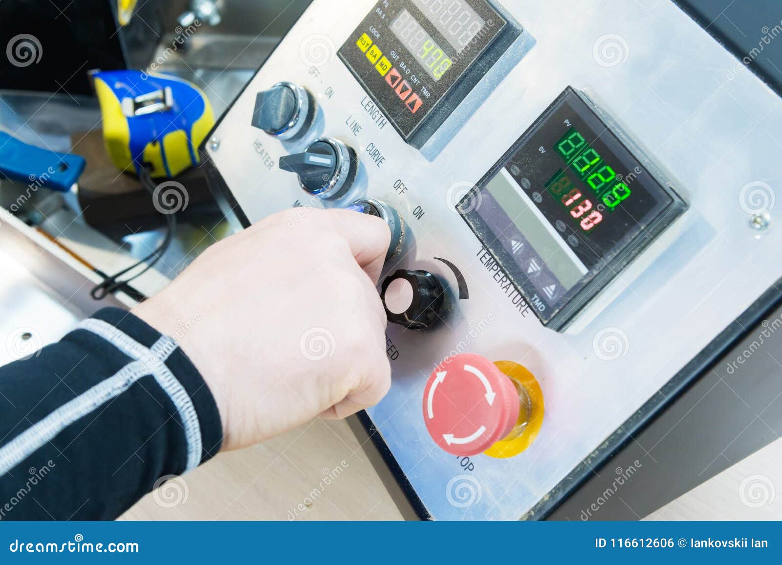 a close-up of a man`s hand holds a rotary switch on the equipment control panel with instruments.