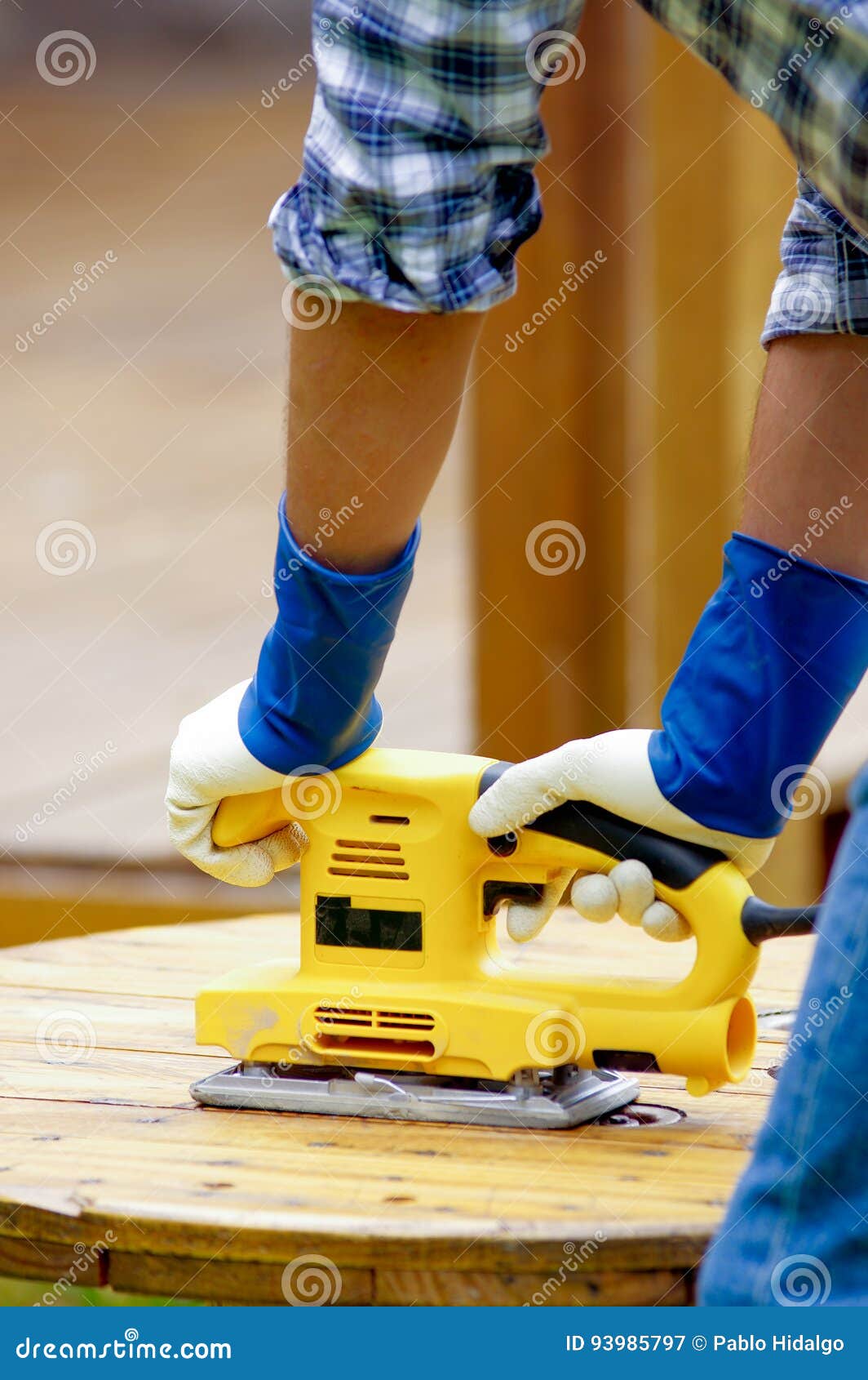 Close Up of a Man Using an Electric Sander on Pine Floor or Table