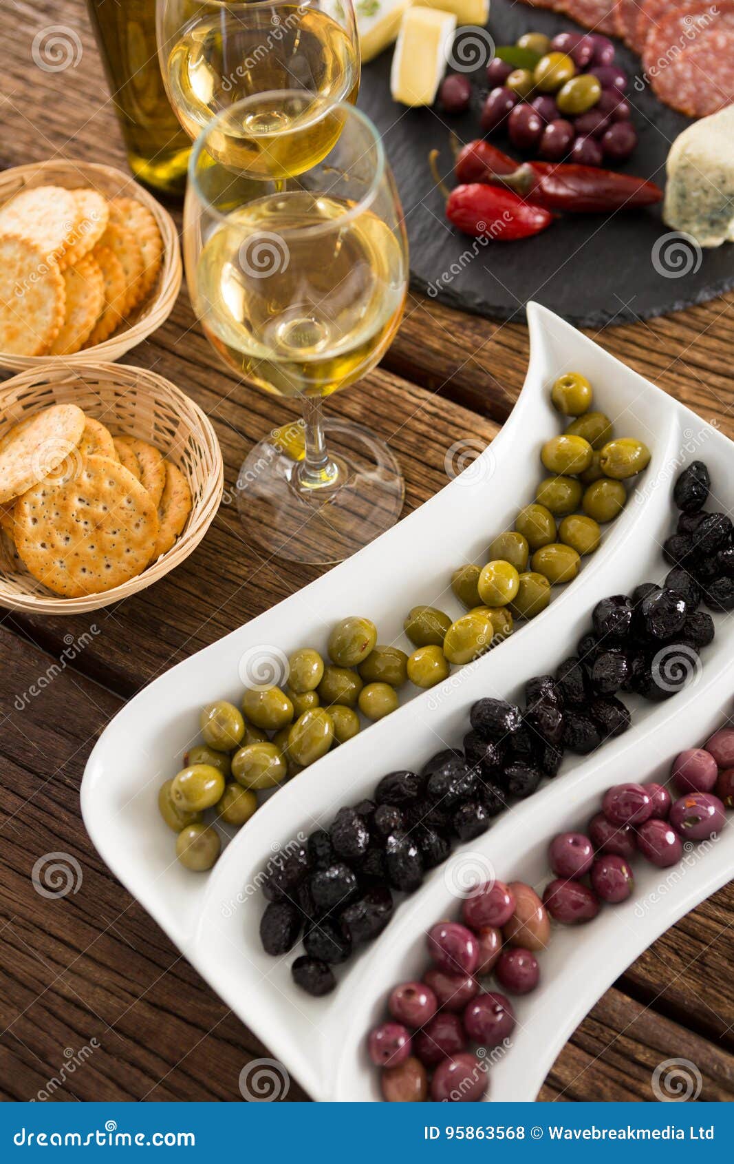 Closeup of Marinated Olives with Bottle of Wine and Food Stock Photo